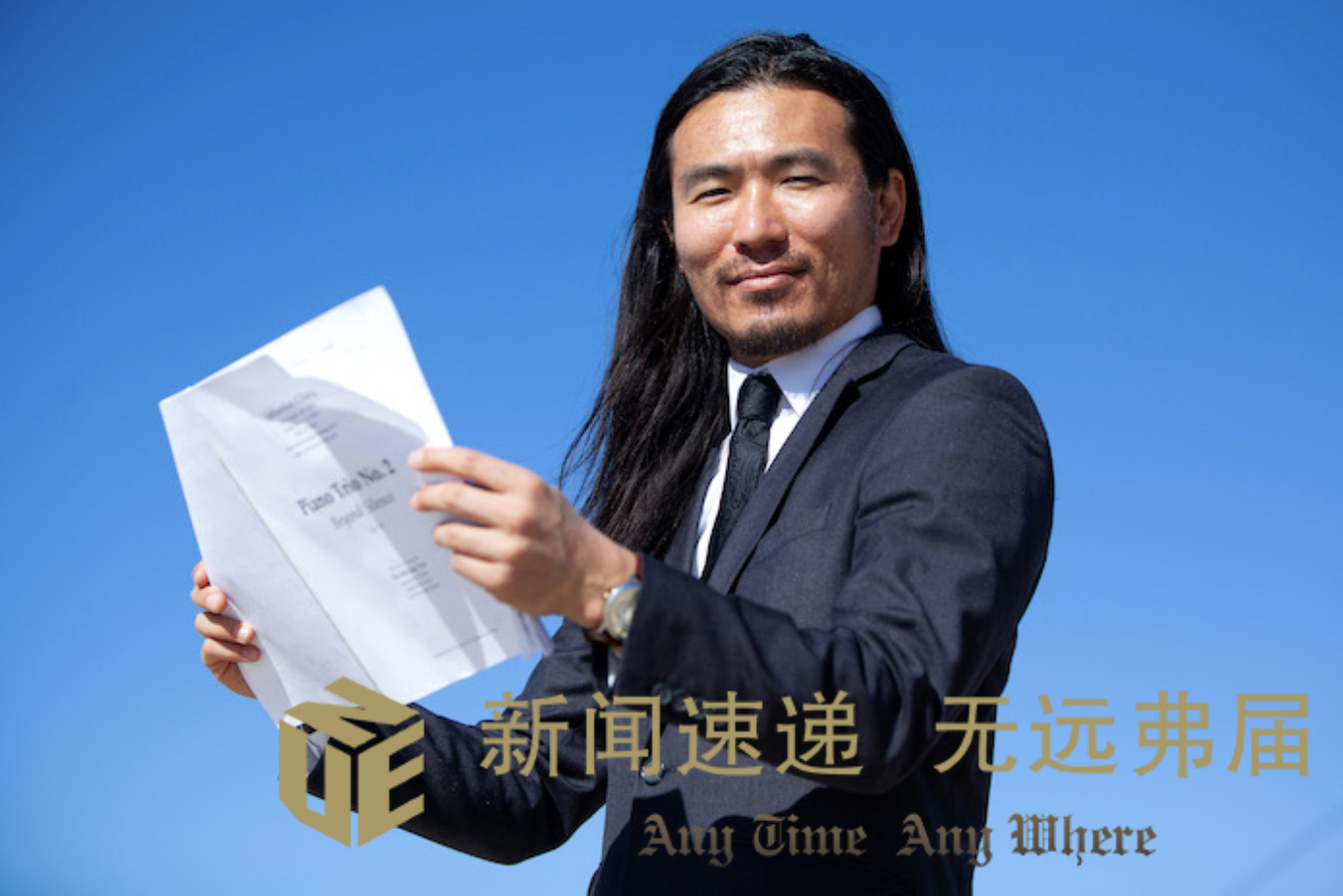 Sebastian Chang stands on the beach with a music score